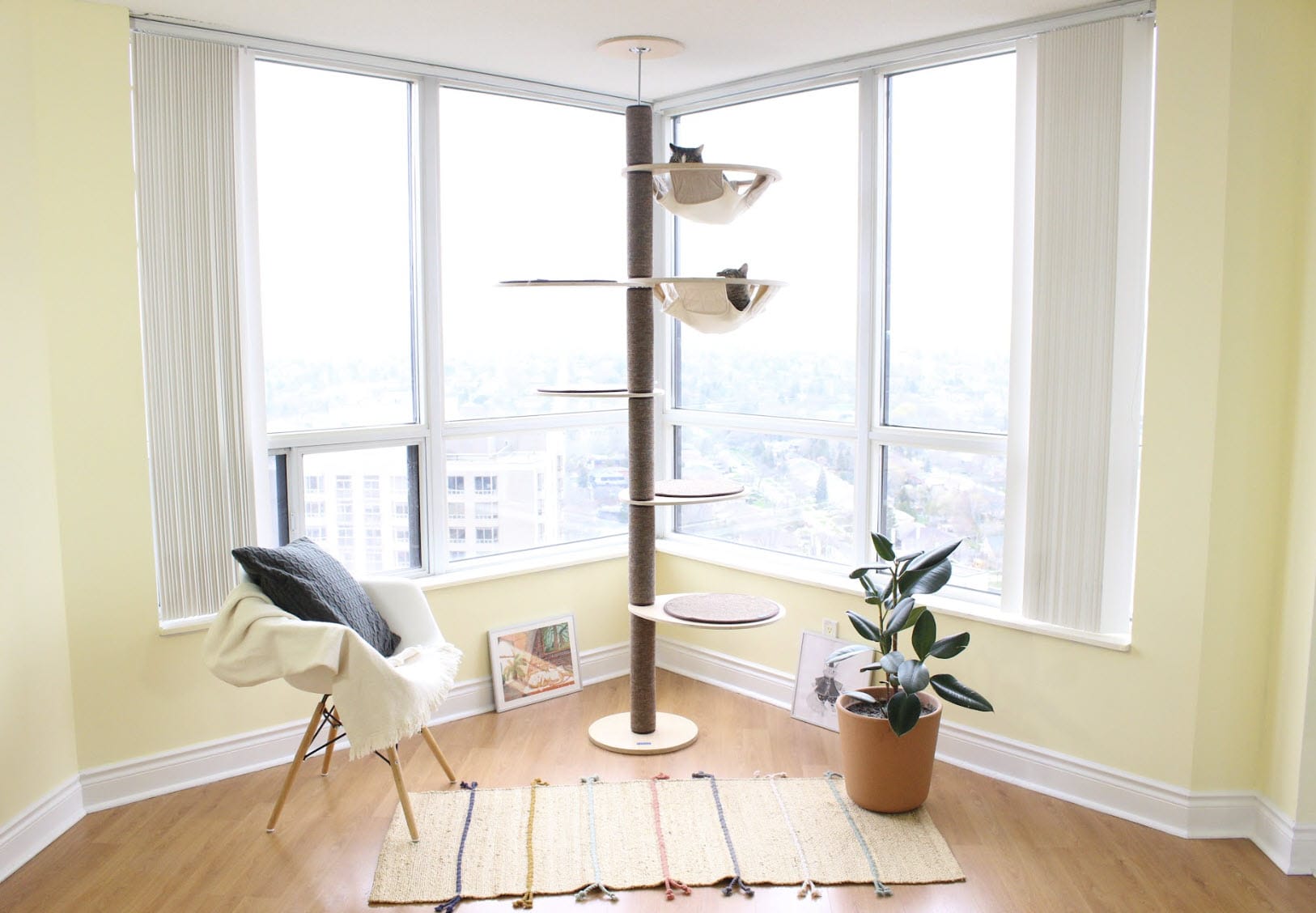 Katpole cat tree with multiple cats climbing and sleeping, made from wood and metal, with two hammocks, in a luxury condo apartment with tasteful decor and great lighting