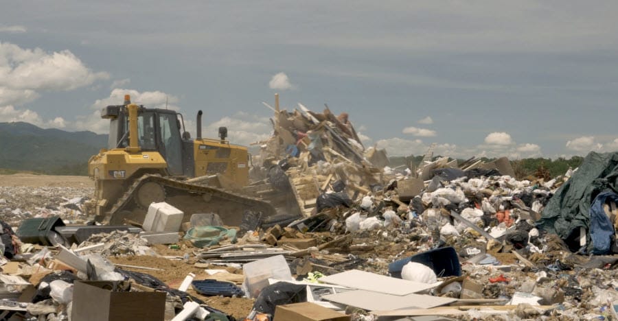CAT Caterpillar with scooper pushing a pile of rubble in a garbage dump